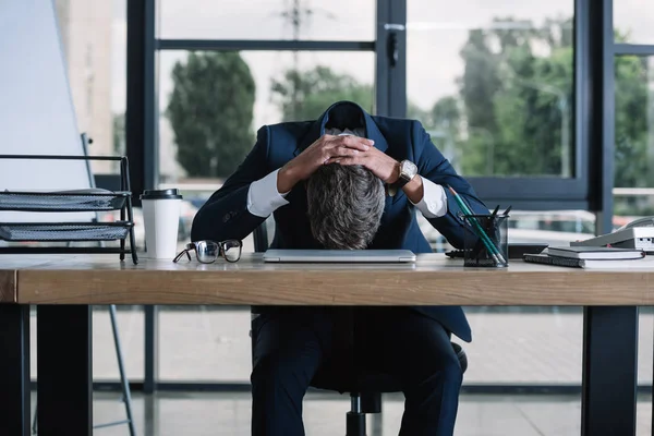 Homme d'affaires assis près du bureau avec tasse en papier et ordinateur portable dans le bureau moderne — Photo de stock