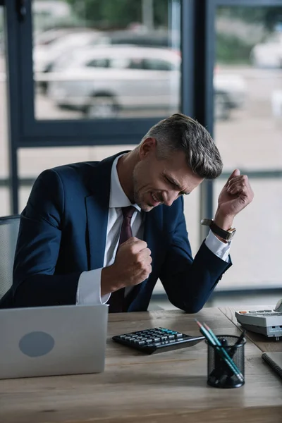 Uomo sconvolto con pugni stretti vicino al computer portatile in ufficio — Foto stock