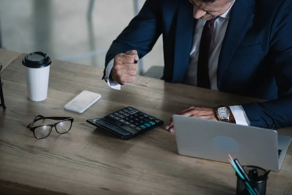 Overhead view of businessman with clenched fist near calculator and laptop — Stock Photo