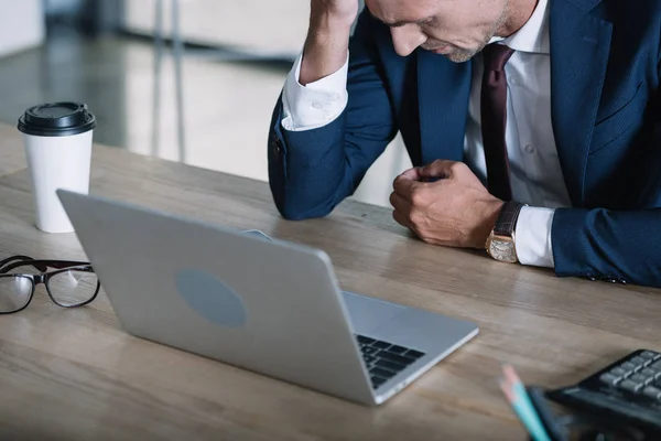 Homem de negócios chateado perto de laptop e copo de papel no escritório — Fotografia de Stock