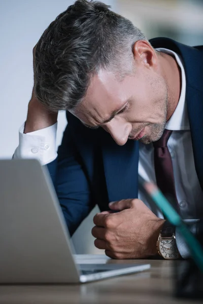 Enfoque selectivo de empresario frustrado en el desgaste formal cerca de la computadora portátil en la oficina - foto de stock