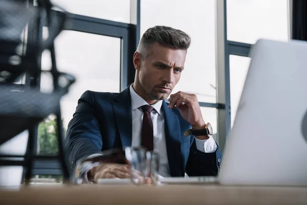 Enfoque selectivo de hombre de negocios utilizando el ordenador portátil en la oficina moderna - foto de stock