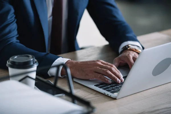 Vue recadrée de l'homme d'affaires tapant sur ordinateur portable dans le bureau — Photo de stock