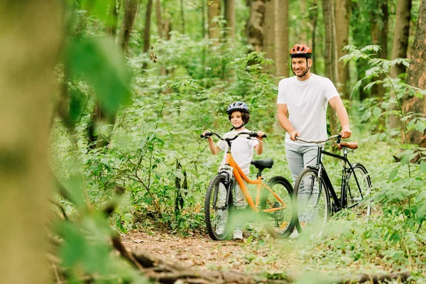 Foyer sélectif du père et du fils marchant avec des vélos dans la forêt — Photo de stock