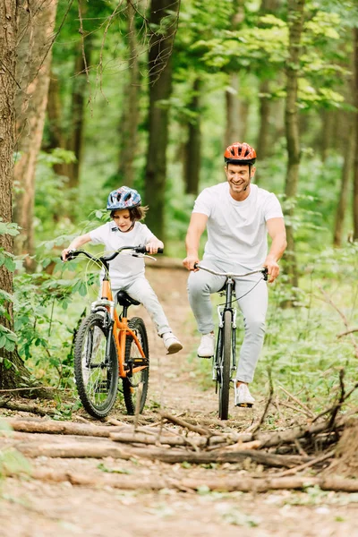 Full length view od father and son riding above fallen brunches — Stock Photo