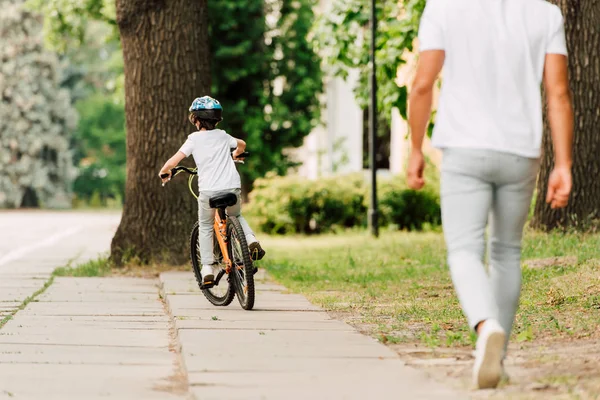 Vue arrière du vélo enfant pendant que le père marche après le fils — Photo de stock