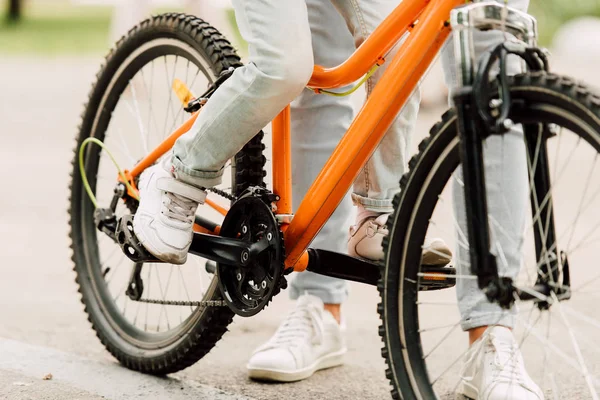 Vista cortada do filho andar de bicicleta, enquanto o pai de pé perto da criança — Fotografia de Stock