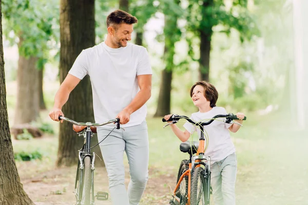 Selective focus of father and son with bicycles looking at each other — Stock Photo