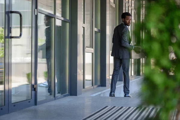 Foco seletivo do empresário afro-americano demitido olhando para trás por que segurando caixa de papelão — Fotografia de Stock
