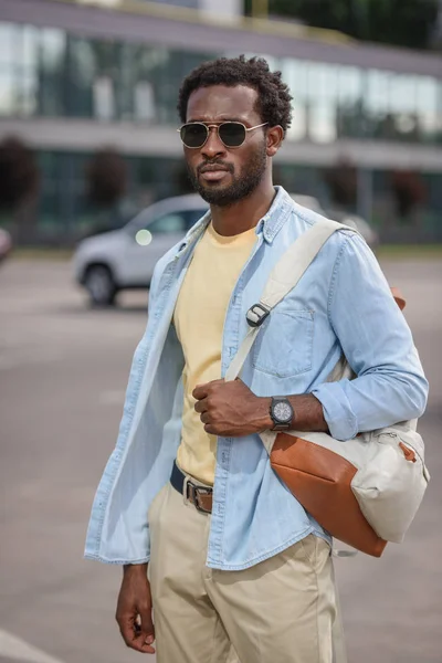 Handsome african american man in sunglasses standing at car parking — Stock Photo