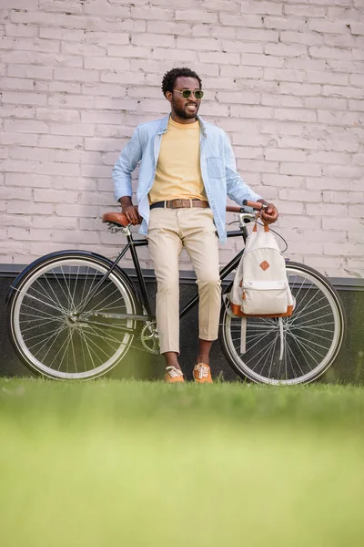 Selective focus of stylish african american man standing with bicycle near brick wall — Stock Photo