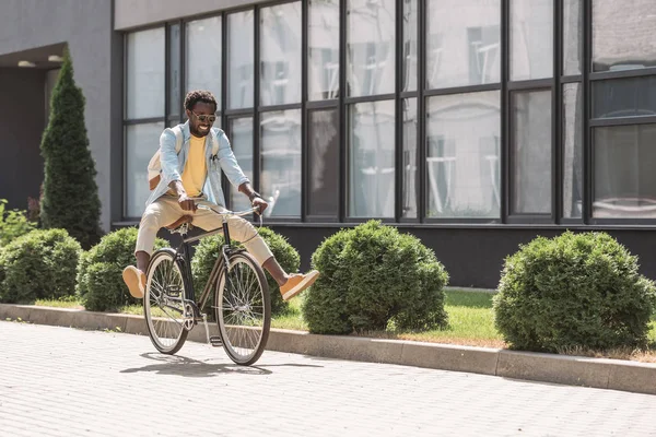 Glücklicher, stilvoller afrikanisch-amerikanischer Mann, der beim Fahrradfahren lächelt — Stockfoto