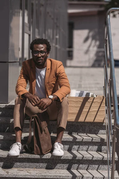 Расстроен африканский американский бизнесмен сидит на лестнице с закрытыми глазами — стоковое фото