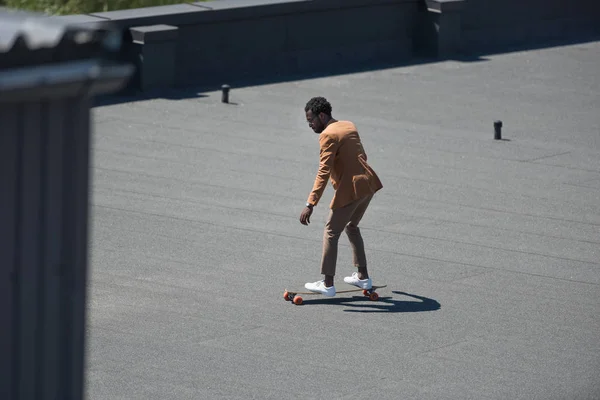 African american businessman riding longoard on sunny rooftop — Stock Photo