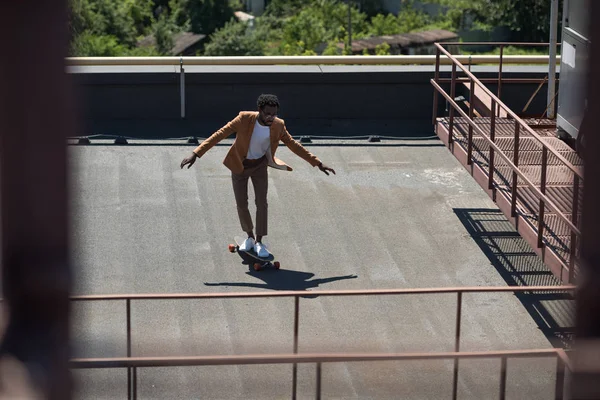 Enfoque selectivo del hombre de negocios afroamericano lonboarding en la azotea soleada - foto de stock