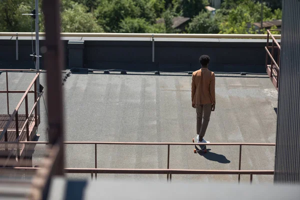 Назад вид на Африканский американский бизнесмен Lonboarding на солнечной крыше — стоковое фото