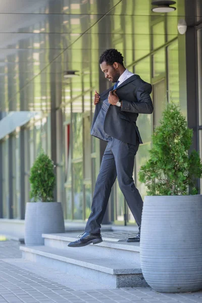 Bonito homem de negócios afro-americano andando em escadas de prédio de escritórios — Fotografia de Stock