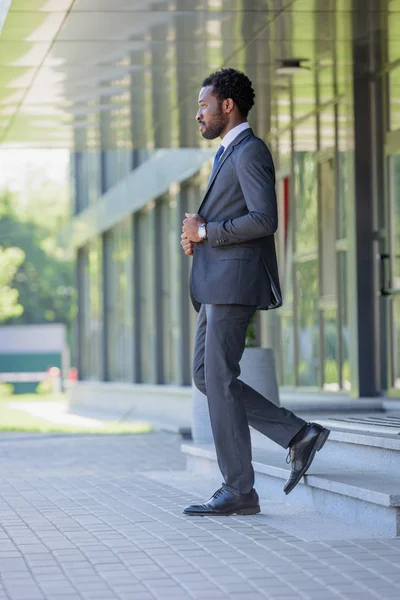 Selbstbewusster afrikanisch-amerikanischer Geschäftsmann im Anzug, der die Treppe eines Bürogebäudes betritt — Stockfoto