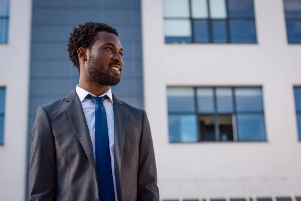Позитивний афроамериканець бізнесмен посміхається, дивлячись на вулицю — стокове фото