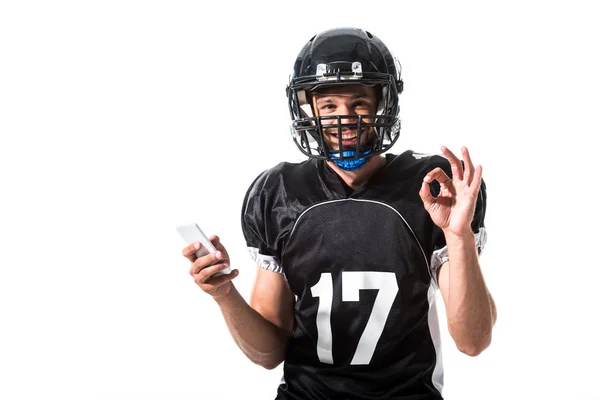 Joueur de football américain avec smartphone et signe OK isolé sur blanc — Photo de stock