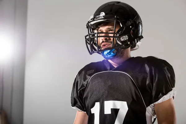 American Football player in helmet on grey with backlit and copy space — Stock Photo