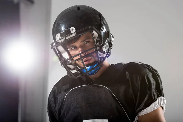 Jugador de fútbol americano en casco en gris con retroiluminación - foto de stock