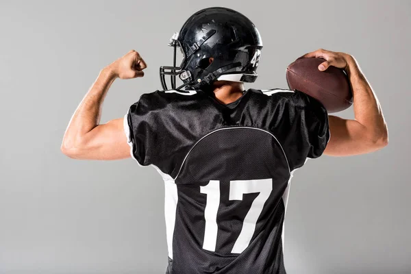 Vista trasera del jugador de fútbol americano con balón aislado en gris - foto de stock