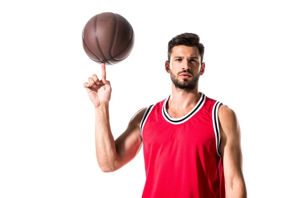 Giocatore di basket che gira sulla palla dito e guardando la fotocamera isolata su bianco — Foto stock