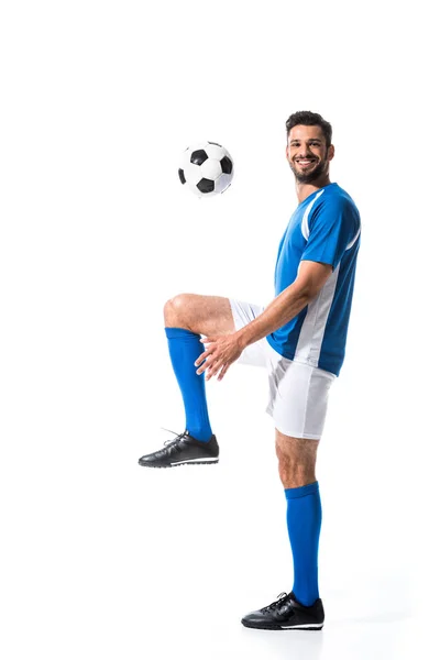 Guapo sonriente jugador de fútbol entrenamiento con pelota aislado en blanco - foto de stock