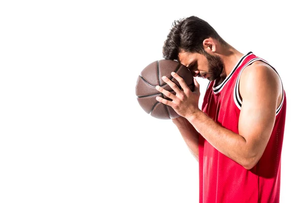 Athletischer Basketballspieler in Uniform lehnt Kopf an Ball isoliert auf weißem Untergrund — Stockfoto