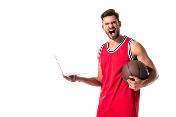 Joueur de basket hurlant avec balle en utilisant un ordinateur portable isolé sur blanc — Photo de stock