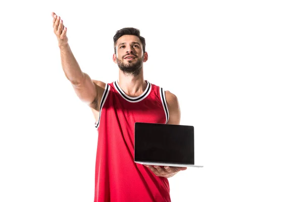 Jugador de baloncesto en uniforme con portátil y mano extendida aislado en blanco - foto de stock