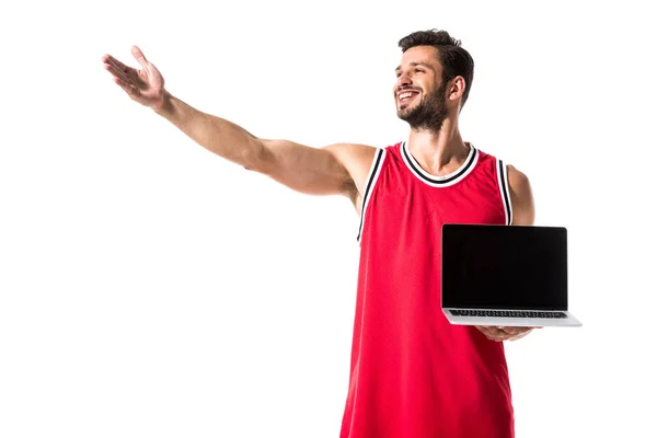 Jugador de baloncesto en uniforme con portátil y mano extendida aislado en blanco - foto de stock