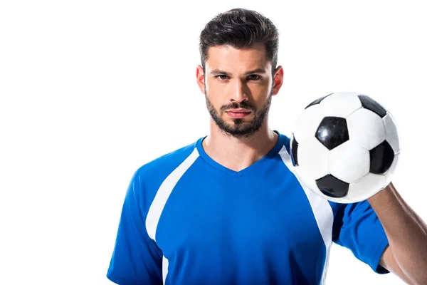 Guapo jugador de fútbol mirando a la cámara y sosteniendo la pelota aislado en blanco - foto de stock