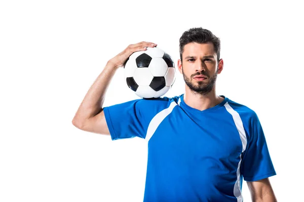 Guapo jugador de fútbol mirando a la cámara y sosteniendo la pelota aislado en blanco - foto de stock