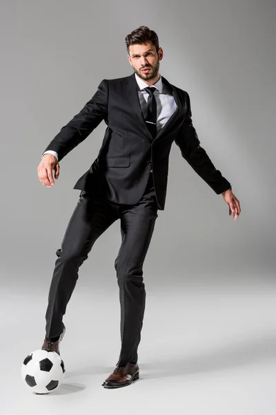 Handsome businessman in formal wear with soccer ball on grey — Stock Photo