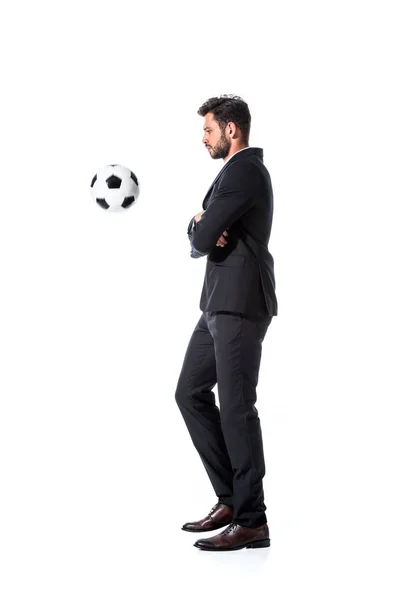 Vista lateral de hombre de negocios guapo en ropa formal con pelota de fútbol aislado en blanco - foto de stock