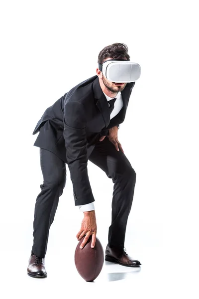 Бизнесмен в формальной одежде и гарнитуре виртуальной реальности с мячом для регби на белом — стоковое фото