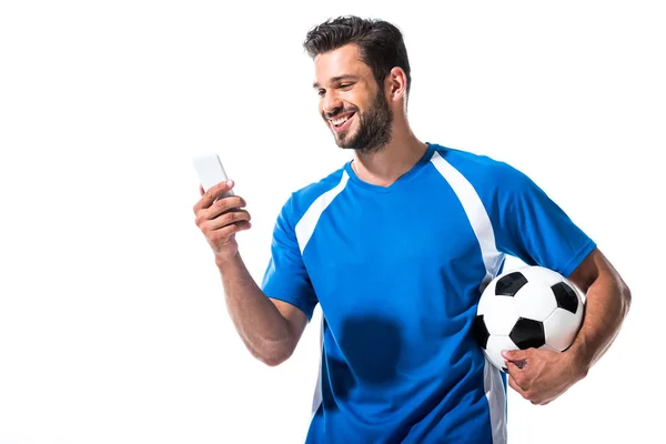 Lächelnder Fußballer mit Ball mit Smartphone auf weißem Grund — Stockfoto