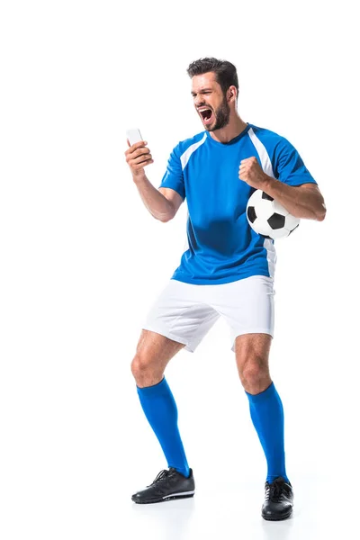 Giocatore di calcio eccitato con palla utilizzando smartphone isolato su bianco — Foto stock