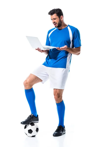 Verwirrter Fußballer mit Laptop und auf Ball stehend isoliert auf weißem Grund — Stockfoto