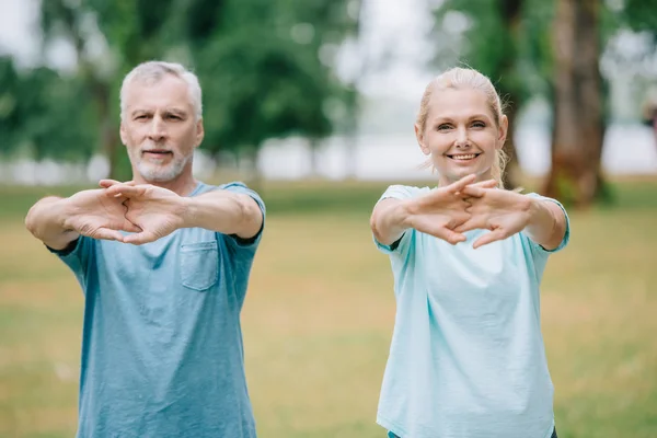 Lächelnde reife Sportler und Sportlerinnen wärmen uns im Park — Stockfoto