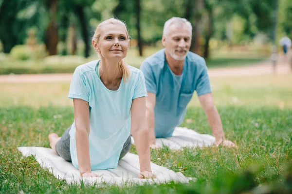 Uomo e donna sorridenti che praticano le pose di yoga di rilassamento sulle stuoie di yoga — Foto stock