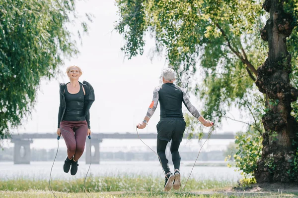 Взрослый спортсмен и спортсменка тренируются с скакалками в парке — стоковое фото