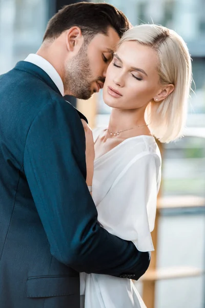 Guapo barbudo hombre de traje coqueteando con atractiva mujer de negocios con los ojos cerrados - foto de stock