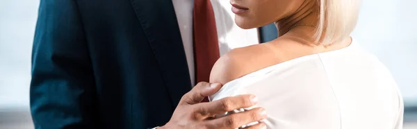 Panoramic shot of man touching shoulder of woman in office — Stock Photo