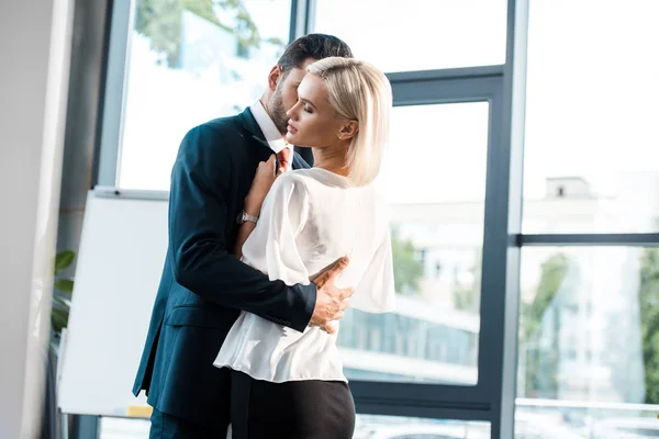 Barbudo homem flertando com mulher enquanto abraçando no escritório — Fotografia de Stock