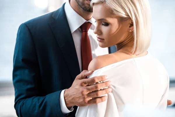 Cropped view of man touching shoulder of attractive woman in office — Stock Photo