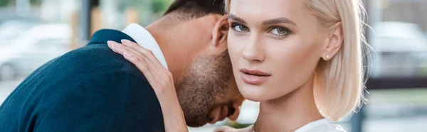 Panoramic shot of attractive woman looking at camera while hugging man in office — Stock Photo