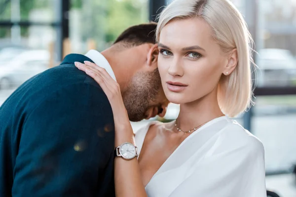 Attractive woman looking at camera while hugging man in office — Stock Photo